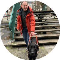 Photo de Aurélien Mory avec son chien guide Stich, un labrador noir.